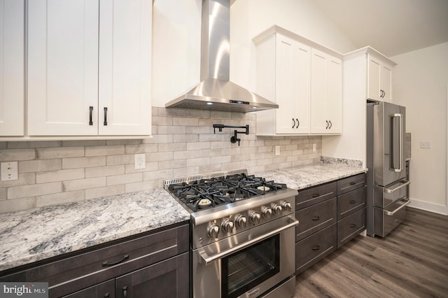 kitchen with white cabinets, high end appliances, wall chimney exhaust hood, dark hardwood / wood-style floors, and light stone countertops