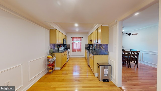 kitchen featuring light wood-style flooring, stainless steel appliances, decorative backsplash, and a decorative wall