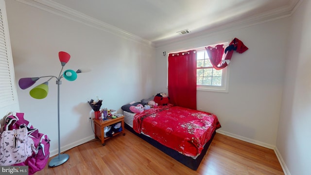 bedroom featuring baseboards, visible vents, ornamental molding, and wood finished floors