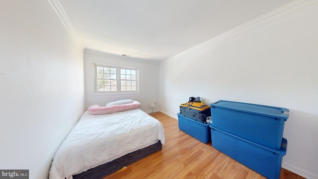 bedroom with ornamental molding, wood finished floors, visible vents, and baseboards