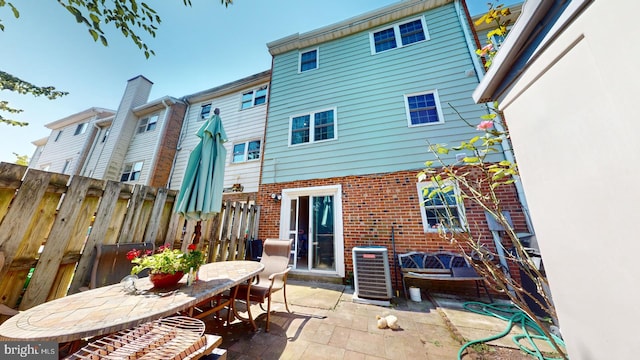 rear view of property featuring a patio area, fence, central AC unit, and brick siding