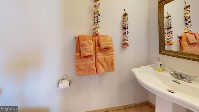 bathroom featuring baseboards, a sink, and tile patterned floors