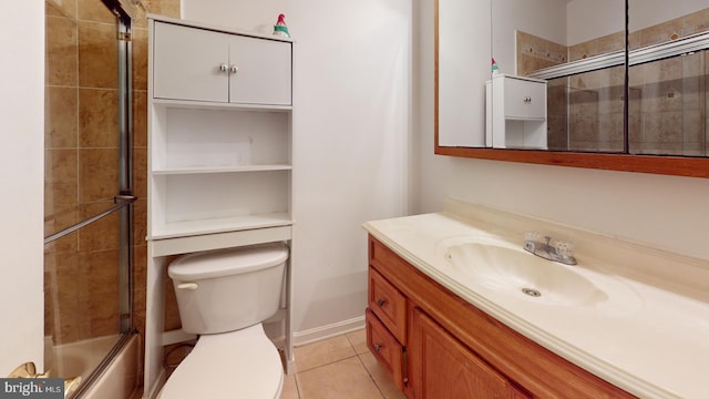 bathroom with toilet, combined bath / shower with glass door, vanity, and tile patterned floors