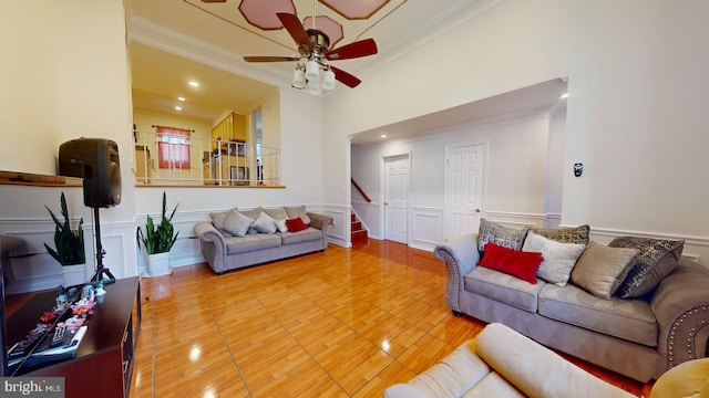 living area with stairs, crown molding, wainscoting, and a decorative wall