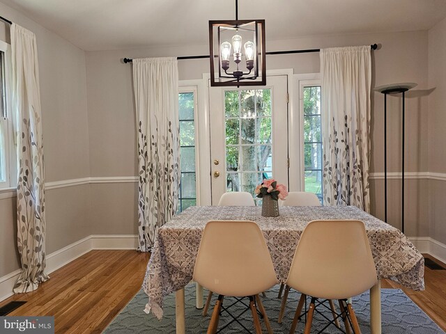 dining space with wood-type flooring and a notable chandelier