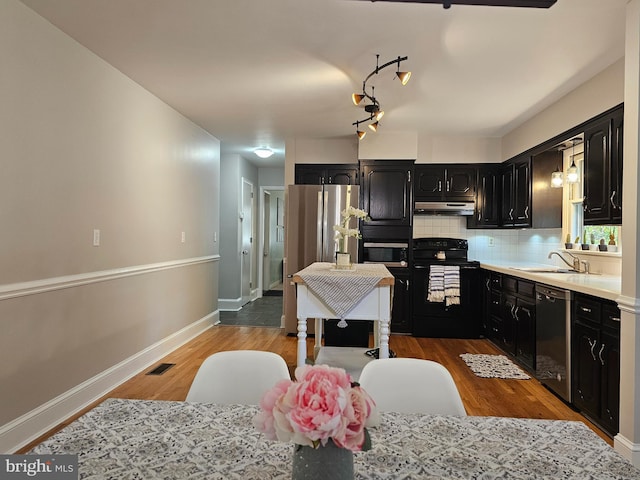 kitchen with hardwood / wood-style floors, sink, decorative backsplash, and black appliances