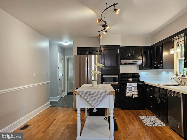 kitchen with backsplash, light hardwood / wood-style floors, rail lighting, sink, and black appliances