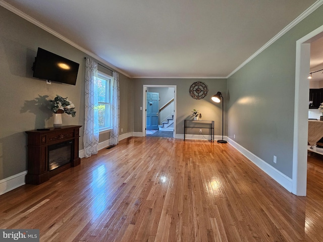 living room with light wood-type flooring, stairs, baseboards, and crown molding