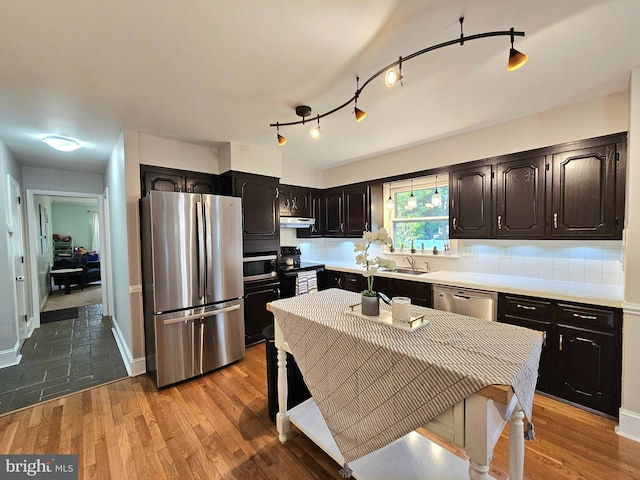 kitchen with sink, appliances with stainless steel finishes, dark brown cabinets, decorative backsplash, and tile patterned floors