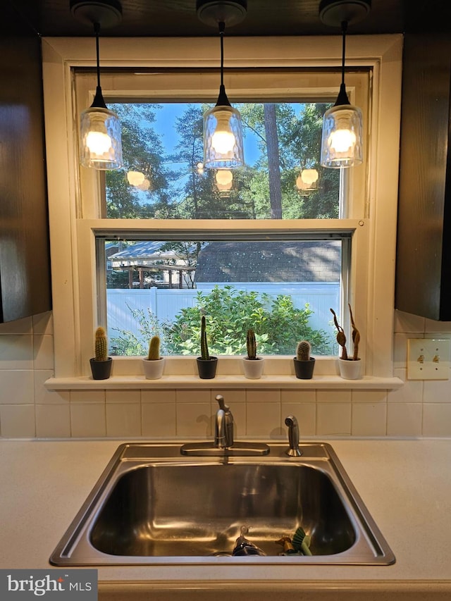 kitchen featuring sink, decorative backsplash, and hanging light fixtures