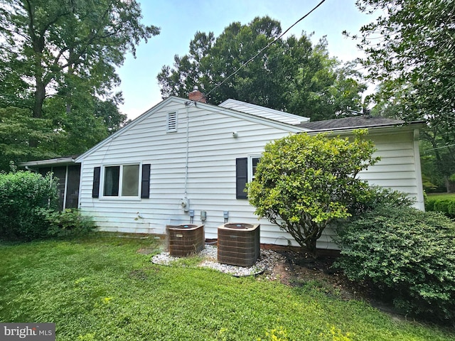 back of property featuring central AC and a lawn