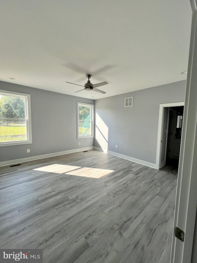 spare room with light wood-style floors, baseboards, visible vents, and ceiling fan