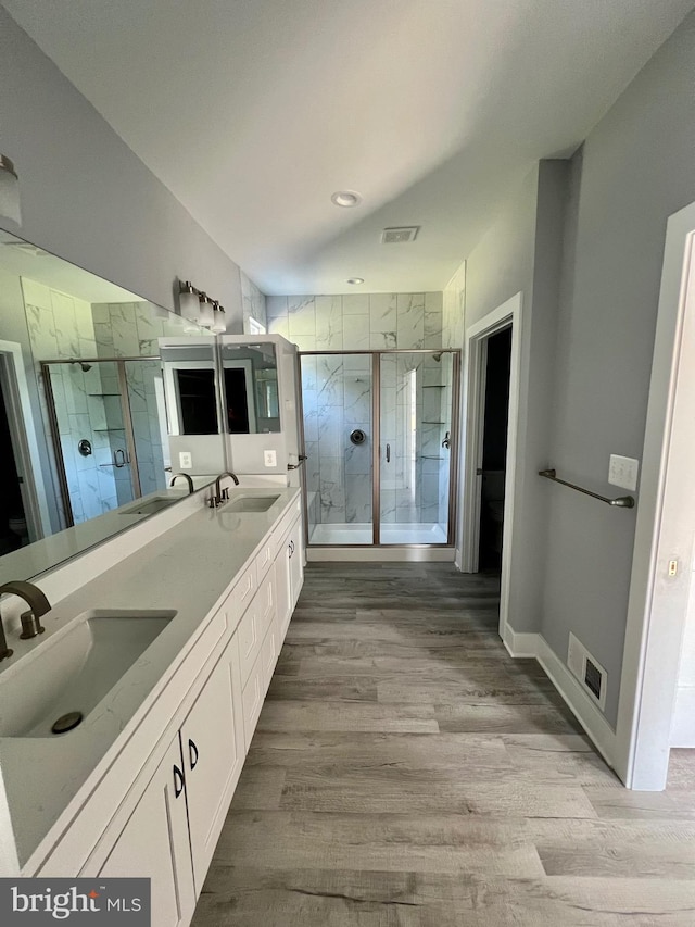 full bath with a sink, a shower stall, and double vanity