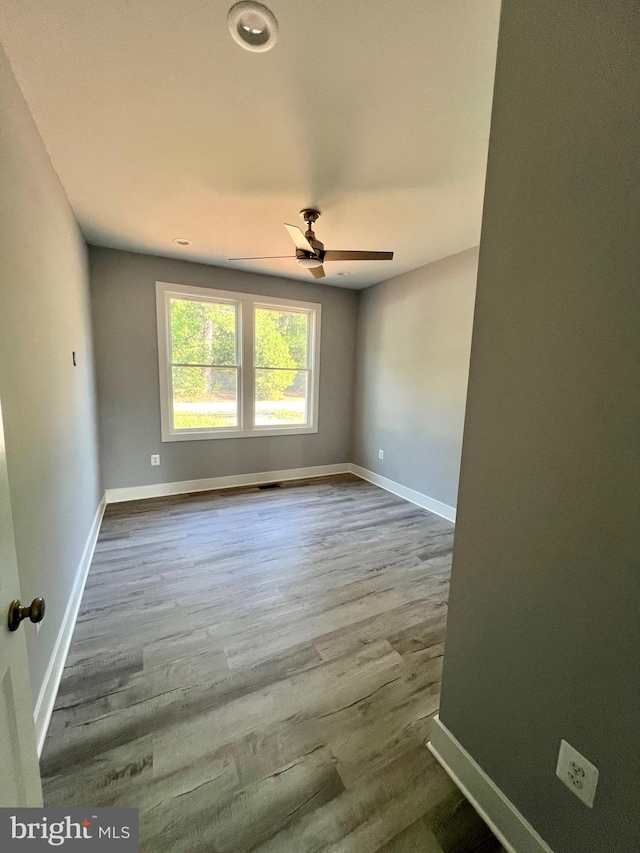 empty room with ceiling fan, baseboards, and wood finished floors