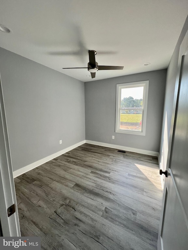 unfurnished room featuring ceiling fan, visible vents, baseboards, and dark wood finished floors