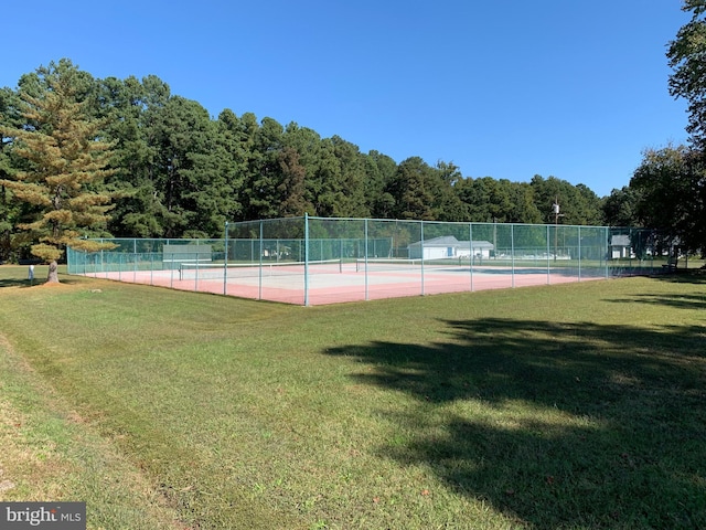 view of tennis court with fence and a lawn