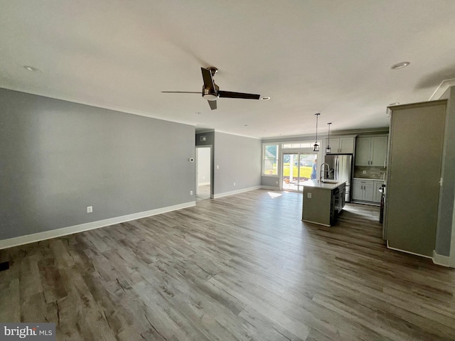 unfurnished living room with dark wood-style floors, a sink, baseboards, and a ceiling fan