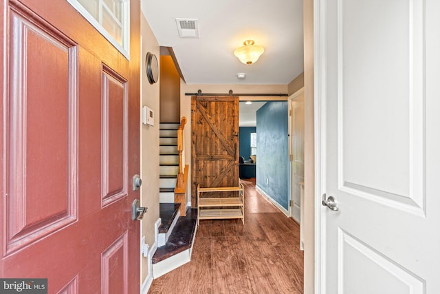 foyer entrance with wood-type flooring and a barn door