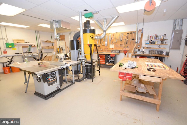 interior space featuring a workshop area, a paneled ceiling, and electric panel