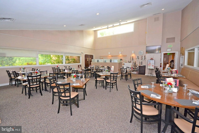 dining space featuring high vaulted ceiling and carpet