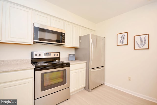 kitchen featuring white cabinets, stainless steel refrigerator, light hardwood / wood-style flooring, and electric range oven