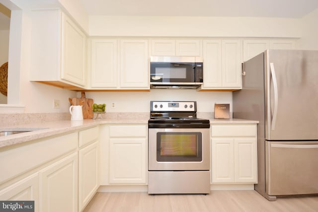 kitchen featuring stainless steel appliances, light stone countertops, and light hardwood / wood-style flooring