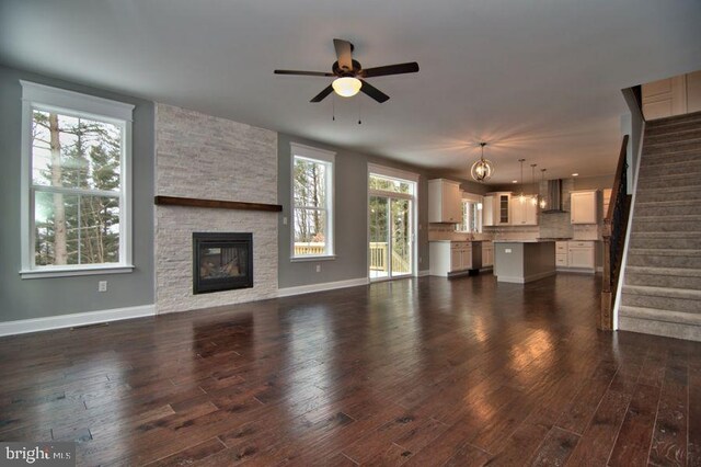 living room featuring a stone fireplace, wood-type flooring, a towering ceiling, and an inviting chandelier