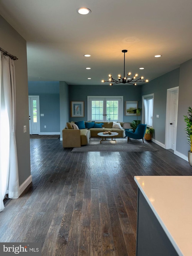 living room with dark wood-type flooring and an inviting chandelier