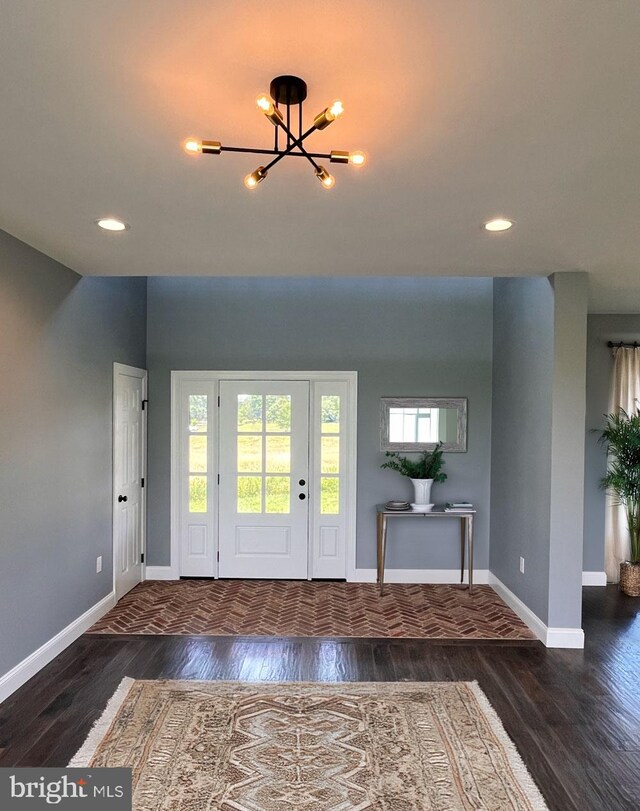 unfurnished living room featuring a chandelier and dark wood-type flooring