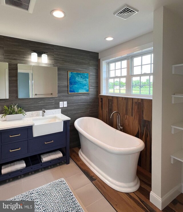 bathroom with walk in shower, vanity, tile patterned floors, and tile walls