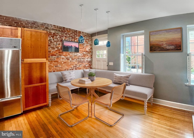 dining room featuring breakfast area, light hardwood / wood-style floors, and brick wall