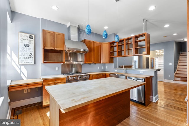 kitchen with light hardwood / wood-style floors, wall chimney exhaust hood, appliances with stainless steel finishes, and a center island