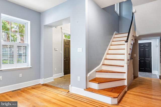 staircase with a healthy amount of sunlight and hardwood / wood-style floors