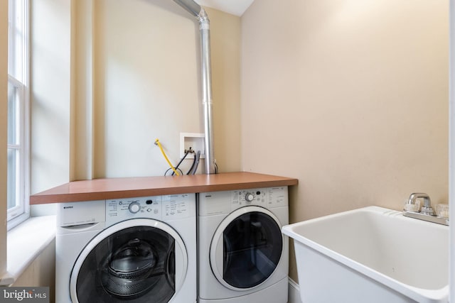 laundry area featuring a healthy amount of sunlight, separate washer and dryer, and sink