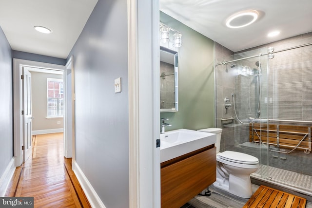 bathroom with a shower with door, vanity, hardwood / wood-style floors, and toilet