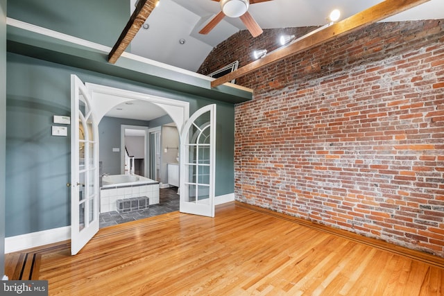 interior space with french doors, wood-type flooring, vaulted ceiling, ceiling fan, and brick wall