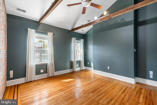 spare room featuring ceiling fan, brick wall, vaulted ceiling with beams, and hardwood / wood-style floors