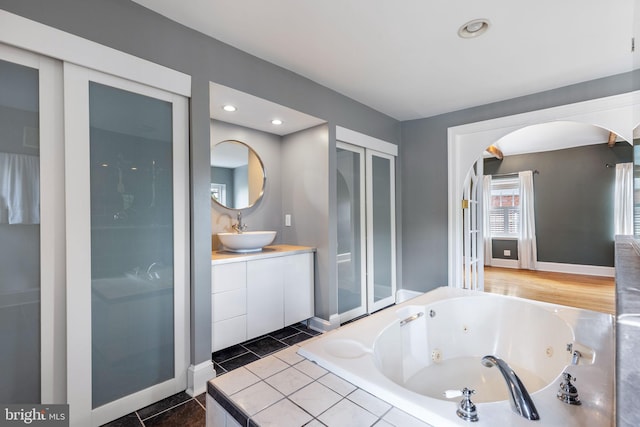 bathroom with vanity, tiled bath, and tile patterned flooring