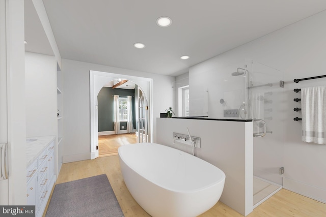 bathroom featuring vanity, hardwood / wood-style floors, and plus walk in shower