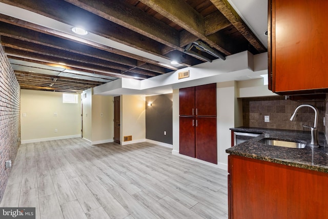 kitchen with sink, light hardwood / wood-style flooring, backsplash, and dark stone countertops