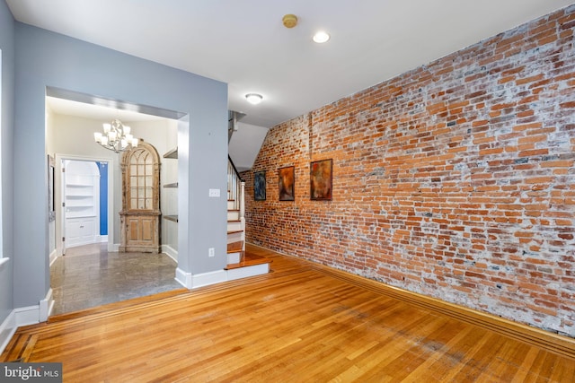 interior space with brick wall, hardwood / wood-style floors, and a notable chandelier