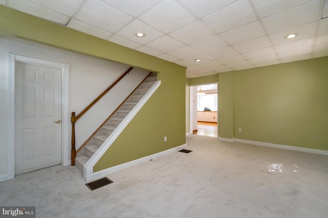 basement featuring a drop ceiling and light carpet