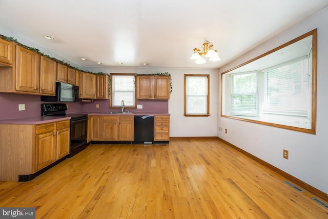 kitchen featuring black appliances, a chandelier, sink, and light hardwood / wood-style flooring