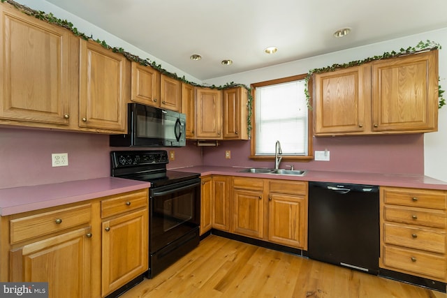 kitchen with black appliances, sink, and light hardwood / wood-style floors