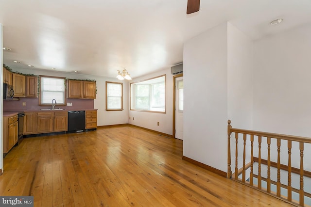 kitchen with light wood-type flooring, black appliances, a wall mounted AC, and sink