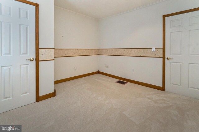 spare room with ornamental molding and light colored carpet