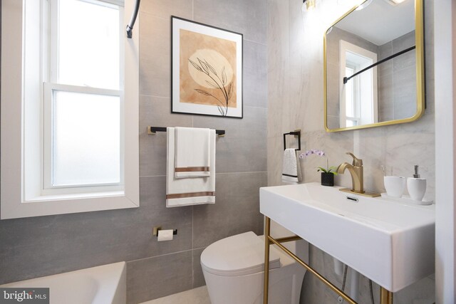 bathroom with bathtub / shower combination, tile walls, and toilet