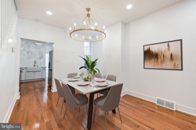 dining room featuring a notable chandelier, sink, and hardwood / wood-style flooring