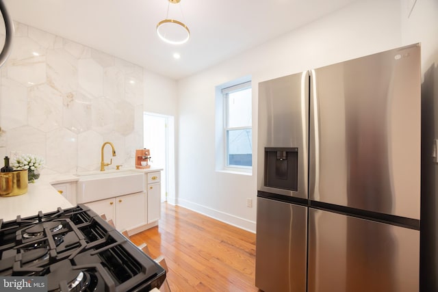 kitchen with tasteful backsplash, white cabinetry, sink, light hardwood / wood-style floors, and stainless steel refrigerator with ice dispenser