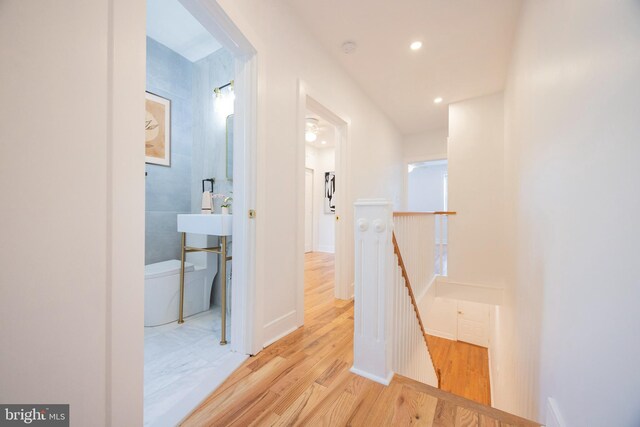 corridor with light wood-type flooring and sink